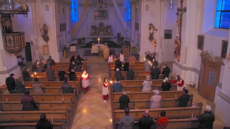 Beginn der Osternacht: Ministranten verteilen in der dunklen Kirche das geweihte Osterlicht