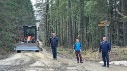 Vom Erfolg der Radweg-Instandsetzung durch die DB Netz AG überzeugten sich Nationalparkleiter Franz Leibl (links), Försterin Silvia Pflug und Bürgermeister Michael Herzog. Für die Reparaturmaßnahme wurde ein Grader (Hintergrund) eingesetzt.