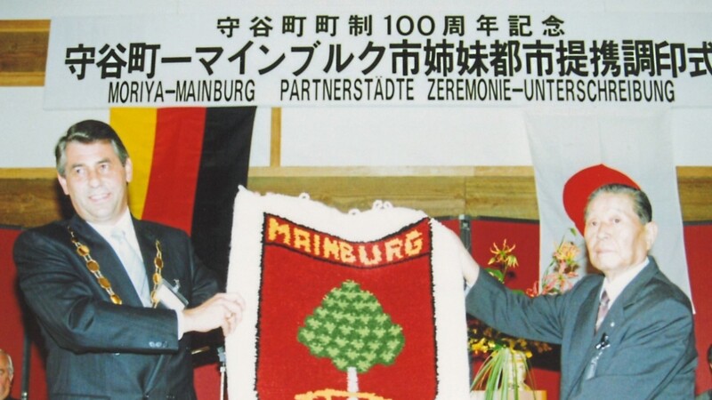 Die Bürgermeister Jin Owada (?) und Sepp Egger unterzeichneten am 3. November 1990 die erste Partnerschaftsurkunde. Als Gastgeschenk gab es einen Wandteppich mit dem Mainburger Wappen.