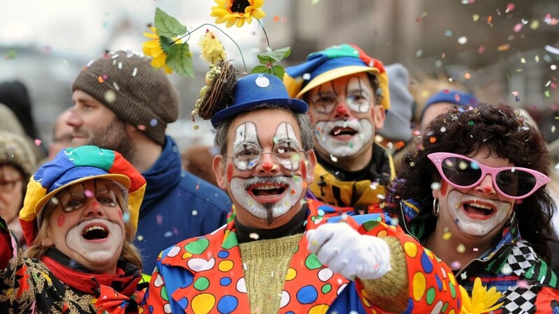 Besucher in Clown-Kostümen werfen in Nürnberg beim Faschingsumzug mit Konfetti.