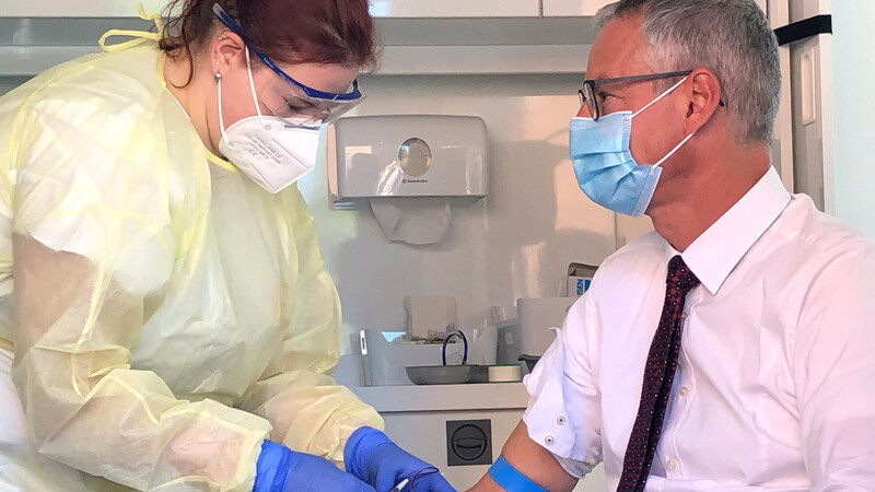 Markus Pannermayr, Oberbürgermeister von Straubing (CSU, r.), lässt sich im RKI-Labor eine Blutprobe entnehmen.