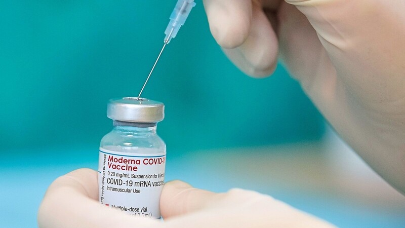 Eine Krankenschwester zieht den Impfstoff des Herstellers Moderna mit einer Spritze auf.