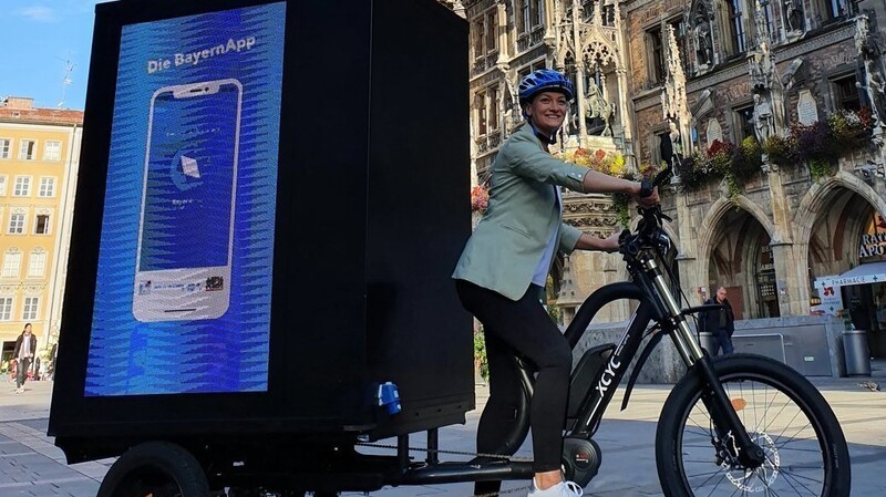 Digitalministerin Judith Gerlach auf ihrem Kampagnen-Rad mit LED-Anzeige zur Bayern-App am Münchner Marienplatz.