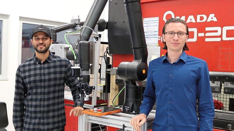 Dieser Cobot kann präzise Blechteile in eine Blechbiegemaschine positionieren. Revanth Prakash (links) und Peter Lingauer sind wissenschaftliche Mitarbeiter am Technologie Campus.