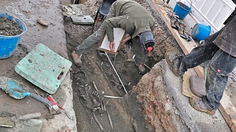 Bei Wind und Wetter haben Archäologen am Dienstag zwei der neu entdeckten Skelette vermessen und den Fundort kartographiert. Zelte haben die Fundstelle vor dem Regen geschützt.