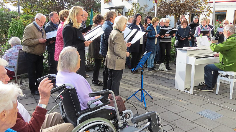 Chorleiter Manfred Plomer und die Sängerinnen und Sänger der Liedertafel beim Konzert auf der Terrasse vor dem Seniorenzentrum.