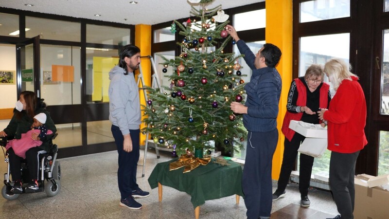 Weihnachtsstimmung im Flüchtlingsheim: Ehrenamtliche Helfer schmücken zusammen mit Bewohnern den Christbaum.