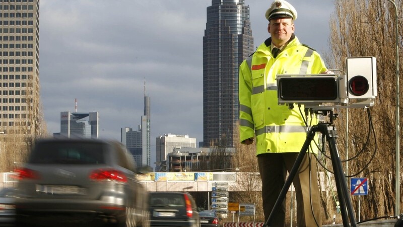 Ein Polizeibeamter steht neben dem Scanner eines "Automatischen Kennzeichenlesesystems".