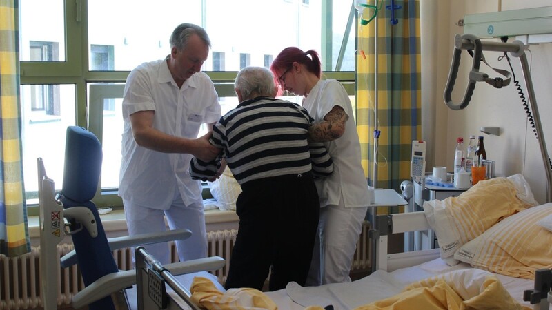 Mit der Krankenschwester Melanie Vogl hilft Helmut Plenk einem pflegebedürftigen Mann in der Arberlandklinik, aufzustehen. Der stellvertretende Landrat lernt an diesem Tag noch einige Tätigkeiten der Krankenhaus-Mitarbeiter kennen.
