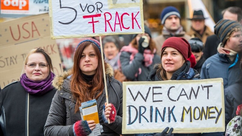 Zwei Teilnehmerinnen der Aktion gegen Fracking halten zwei Transparente mit den Aufschriften "Es ist 5 vor Frack" und "We can't drink money" in den Händen.