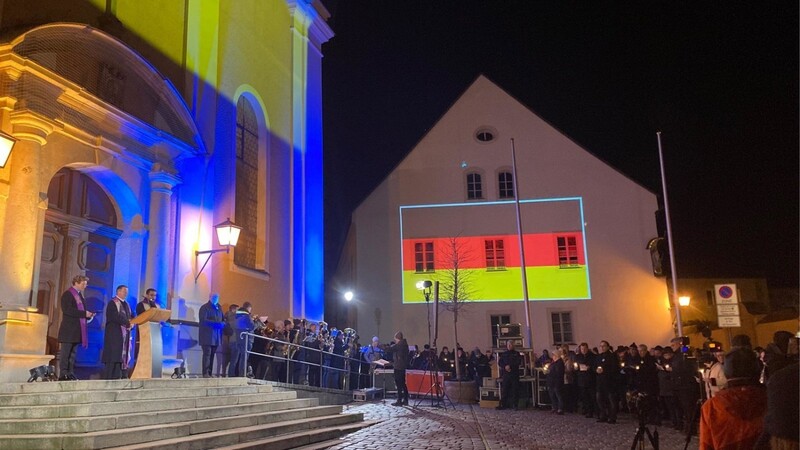 Die Flaggen der Ukraine und Deutschlands leuchten an den Fassaden des Pfarrhofs sowie der Kirche Sankt Jakob.