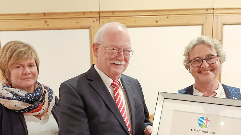 Bürgermeisterin Christine Hammerschick (rechts) und Geschäftsstellenleiterin Ursula Heller gratulieren mit einer Urkunde Karl Mühlbauer zur Ernennung zum Altbürgermeister.