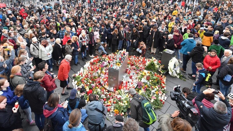 Halle: Menschen stehen auf dem Marktplatz neben Blumen und Kerzen, um ein Zeichen gegen Gewalt zu setzen und um zu Trauern. Bei Angriffen mitten in Halle an der Saale in Sachsen-Anhalt sind am 09.10.2019 zwei Menschen erschossen worden.
