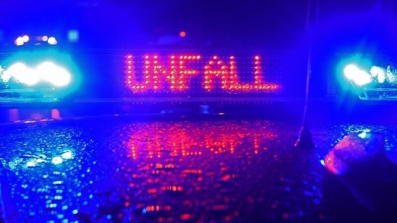 Während einer Unfallaufnahme spiegelt sich das Blaulicht und der LED- Schriftzug "Unfall" auf dem nassen Dach eines Polizestreifenwagens. Foto: Stefan Puchner/dpa