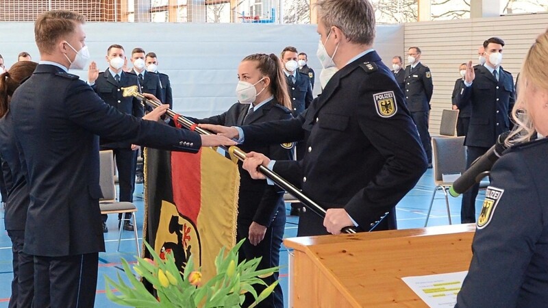 Polizeihauptkommissarin Nicole Fischl (am Pult) und Polizeihauptkommissar Anton Scheuerer (Fahne) nahmen die Vereidigung der neue Kolleginnen und Kollegen vor.