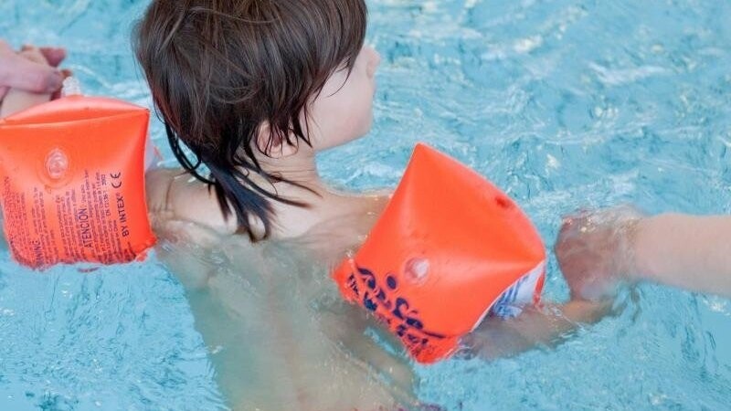 Eine Junge lernt mit Schwimmflügeln schwimmen. Foto: Patrick Pleul/dpa-Zentralbild/dpa/Symbolbild