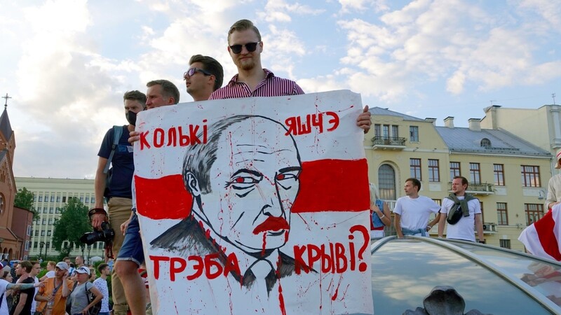 "Wie viel Blut braucht es noch?" steht auf dem Plakat mit dem Gesicht von Machthaber Lukaschenko, das ein junger Mann auf dem Unabhängigkeitsplatz hält.