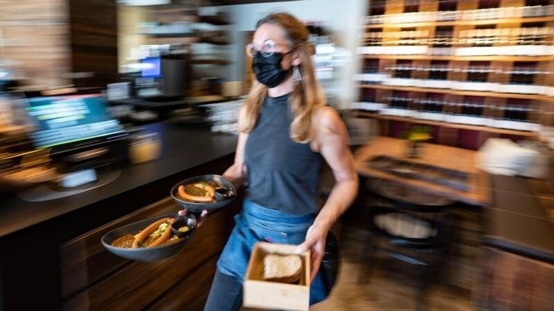 Eine Kellnerin trägt in einem Restaurant Essensteller. (Archivbild).