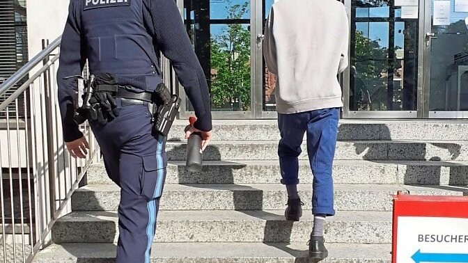 Der Angeklagte und ein Polizeibeamter vor dem Landgericht in Landshut.