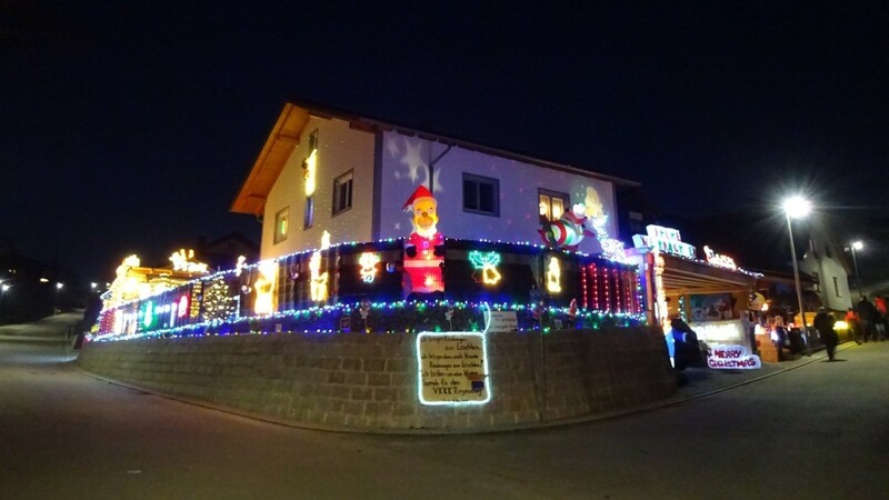Schon von weitem sieht man das Weihnachtshaus leuchten. Zaun und Haus sind leuchtend dekoriert.
