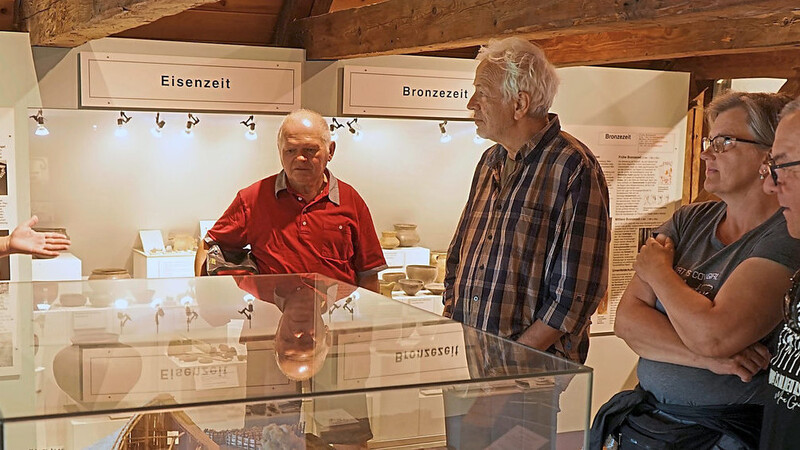 Museumspädagoge Marton Dregelyi (l.) mit einer kleinen Besuchergruppe an dem Modell eines großen Bauerngehöfts, wie es vor rund 7 000 Jahren die Menschen der Epoche der Stichbandkeramik gebaut haben.