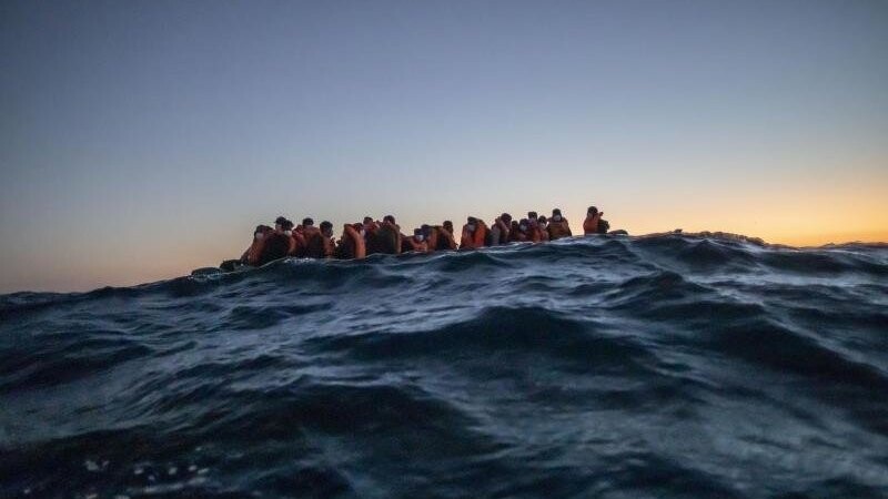 Migranten aus verschiedenen afrikanischen Nationen warten in einem Boot vor der libyschen Küste im Mittelmeer auf Helfer.