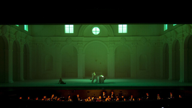 Leporello (Vito Priante) mit Elvira (Federica Lombardi) bei der Registerarie im grünen Licht des Kopierers
