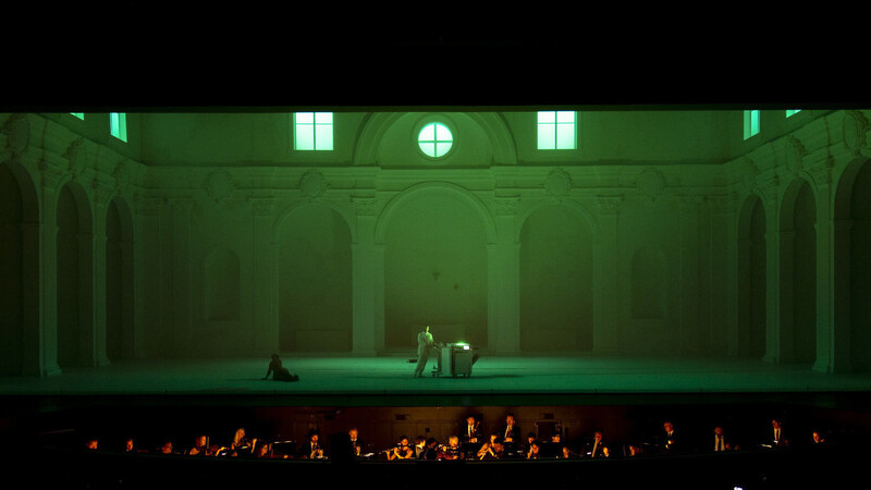 Leporello (Vito Priante) mit Elvira (Federica Lombardi) bei der Registerarie im grünen Licht des Kopierers