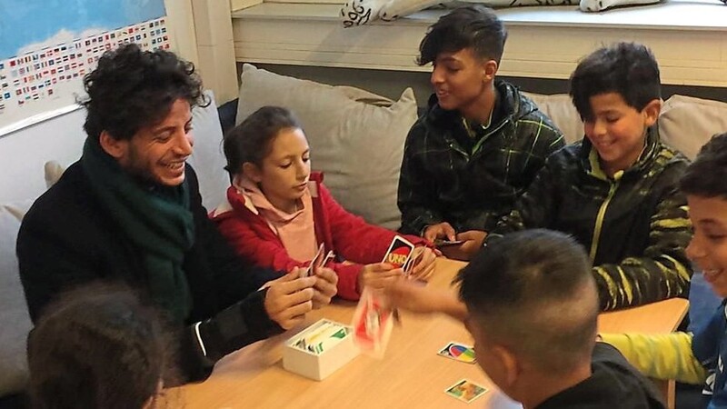 Zaid Abdul Sattar (l.) beim Kartenspielen mit Kindern in der Gruppe "Sport und Spiel" im Regensburger Ankerzentrum.