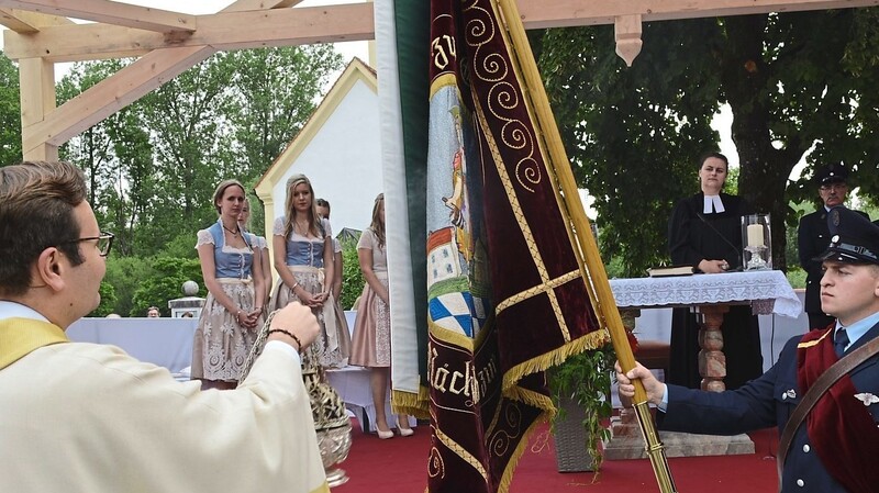 Pfarrvikar Franz Pfeffer segnete die Fahne der FF Pielweichs, nachdem man die Festbänder angebracht hatte. Im Hintergrund: Pfarrerin Karolin Gerleigner.