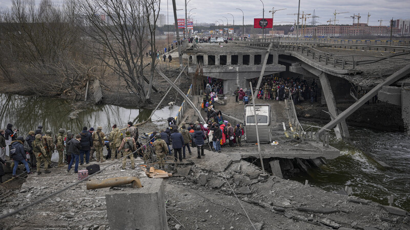Menschen überqueren den Fluss Irpin auf einem improvisierten Weg unter einer durch einen russischen Luftangriff zerstörten Brücke, während sie aus der Stadt Irpin fliehen. Russische Truppen marschierten am 24. Februar in die Ukraine ein.