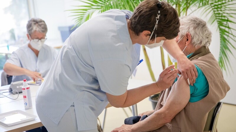 Eine Mitarbeiterin des Robert-Bosch-Krankenhauses in Stuttgart impft einen älteren Mann gegen das Coronavirus.