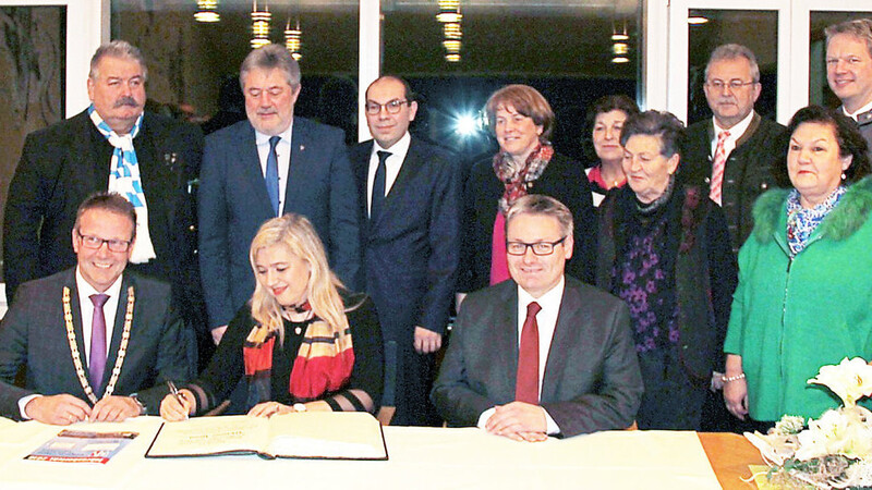 Melanie Huml trägt sich im Beisein von Bürgermeister Johann Grau (links), Josef Zellmeier (rechts) und weiteren politischen Amtskollegen in das Goldene Buch der Gemeinde ein.
