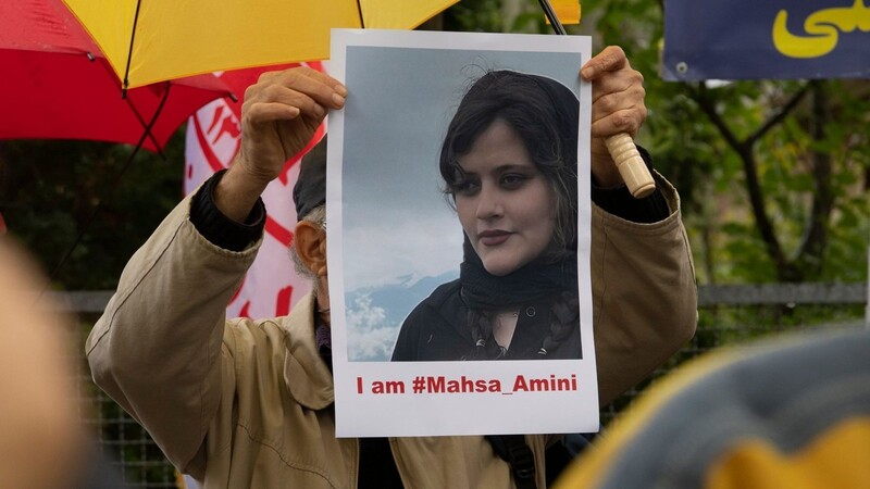 Bei einem Protest in Berlin hält ein Mann ein Bild der verstorbenen Mahsa Amini in Händen.