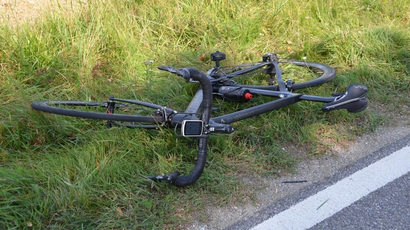 Ein Rennradler stürzte nach einem Zusammenstoß mit einem Auto schwer. Das Rad des Verunglückten liegt am Straßenrad.