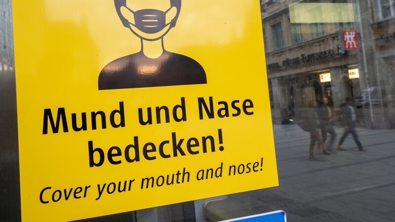Ein Schild fordert am Marienplatz in München zum Tragen eine Mund-Nasen-Bedeckung auf. Aufgrund der steigenden Corona-Zahlen zieht die Regierung in vielen Regionen die Zügel wieder fester an.