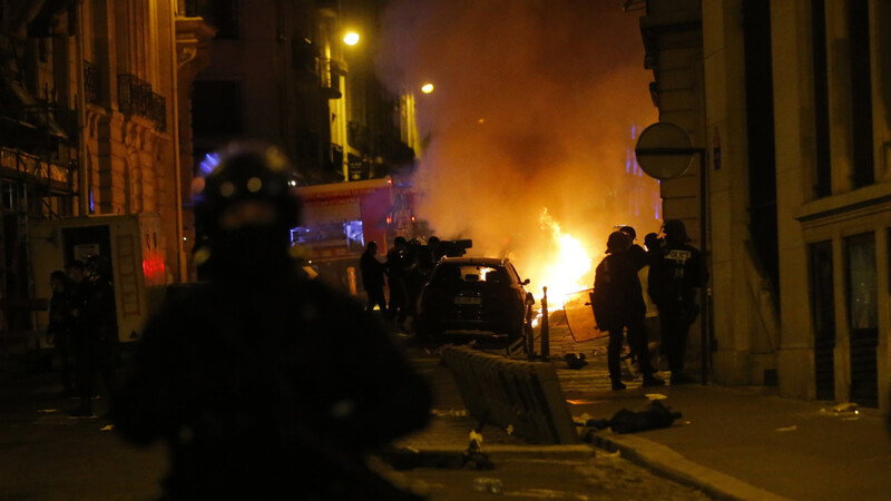 Polizisten in der Nähe der Champs-Elysées. Im Hintergrund brennt ein Auto.