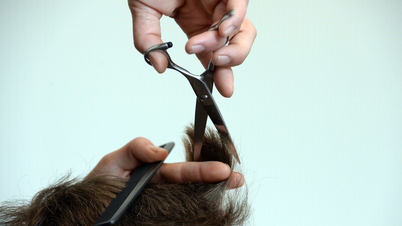 Ein Friseur schneidet die Haare. (Symbolbild)