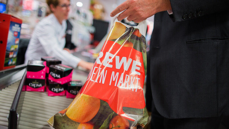 Ein Kunde packt am 31.05.2016 an der Kasse eines Rewe-Marktes in Düsseldorf (Nordrhein-Westfalen) seine Einkäufe in eine Tragetasche aus Plastik. Die Rewe Group möchte eine Reduzierung von Plastikmüll erreichen und verzichtet in Zukunft in ihren Märkten auf Plastiktüten.