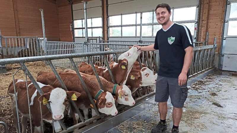 Der junge Bio- Landwirt Markus Weber mit seinen Kälbern im eingestreuten Tieflaufstall.