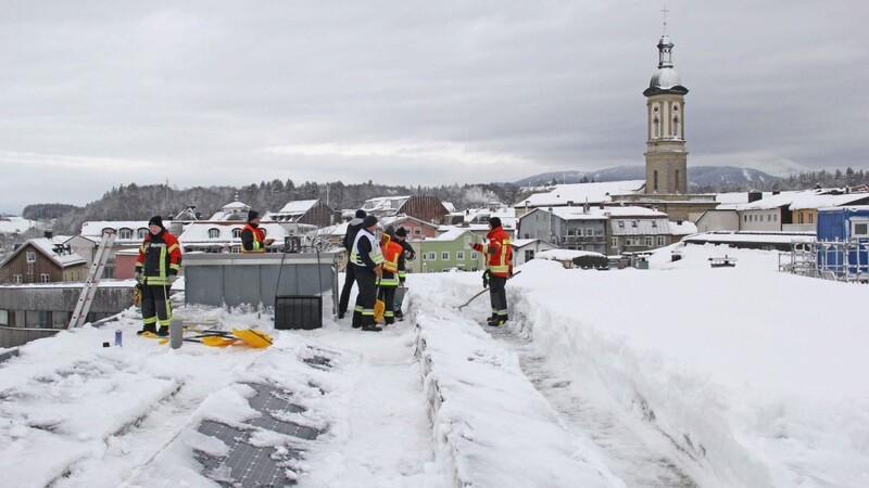 Hier wird von den Feuerwehrleuten ein Flachdach in Traunstein vom Schnee befreit.