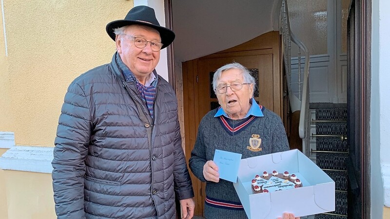 Rudi Prösl (l.) überreicht seinem ehemaligen Lehrer Hellmut Pulkert zum 90. Geburtstag eine Torte und viele Grüße von den Klassenkameraden.