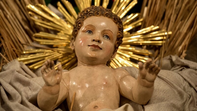Eine Holzfigur von Jesus liegt in einer Krippe in der Frauenkirche in München.