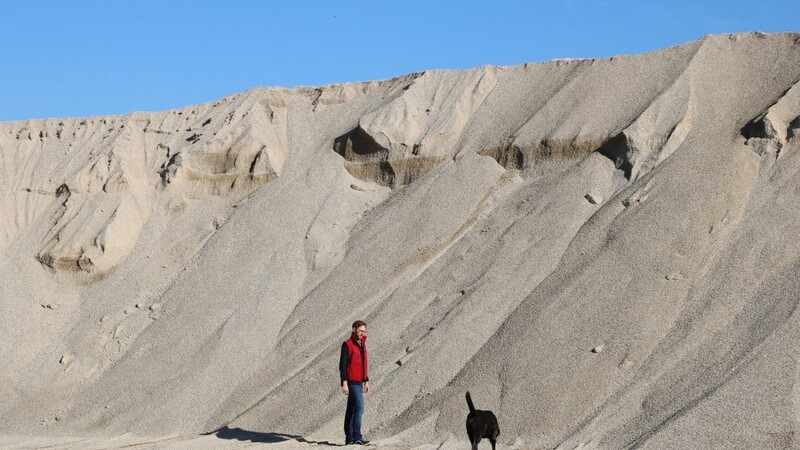 Johannes Wolf steht mit seinem Hund an einer Kieshalde im Attinger Abbaugebiet. Doch was auf Kinder wie ein riesiger, verlockender Sandhaufen zum Spielen wirkt, birgt Gefahren: Kommt der Kies ins Rutschen, kann er schnell Menschen unter sich begraben.