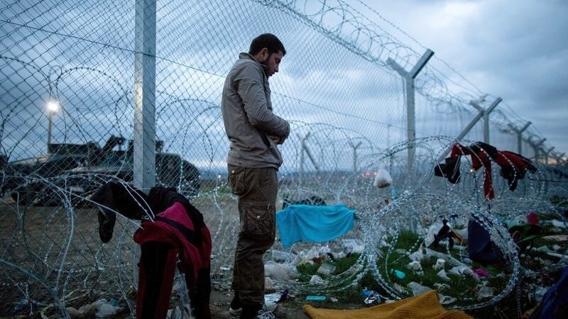 Ein Mann betet am 07.03.2016 im Flüchtlingslager in Idomeni an der Grenze zwischen Griechenland und Mazedonien zwischen Stacheldrahtrollen am Grenzzaun. Nur noch wenige Flüchtlinge aus Syrien und dem Irak werden täglich über die Grenze gelassen.