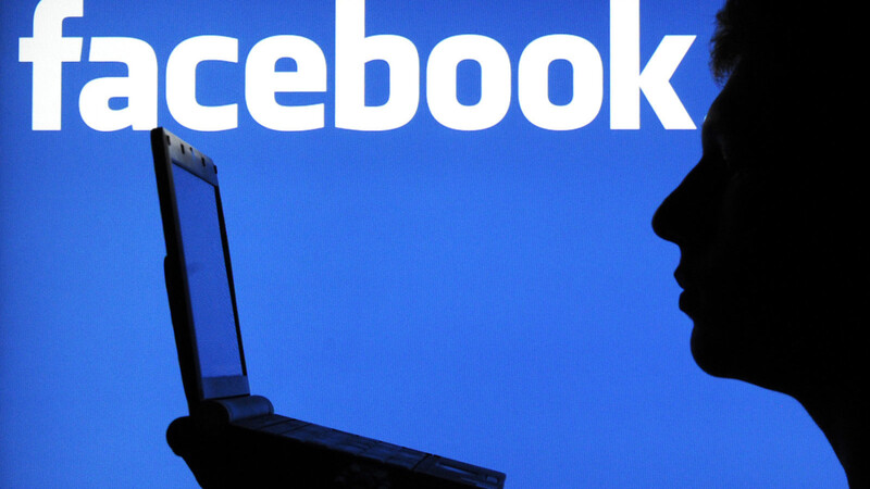 Die Silhouette eines jungen Mannes ist vor einem Bildschirm mit dem Schriftzug des Online-Netzwerks Facebook zu sehen.