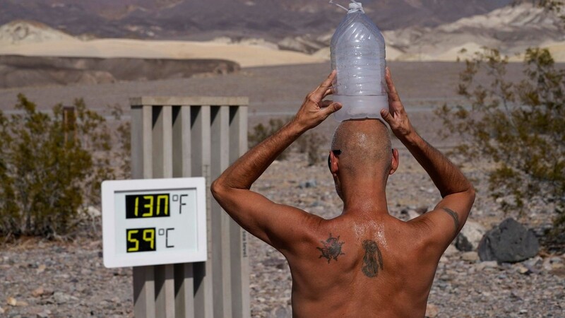 Ein Mann kühlt sich im "Death Valley"-Nationalpark mit einer mit Eiswasser gefüllten Plastikflasche auf dem Kopf ab.