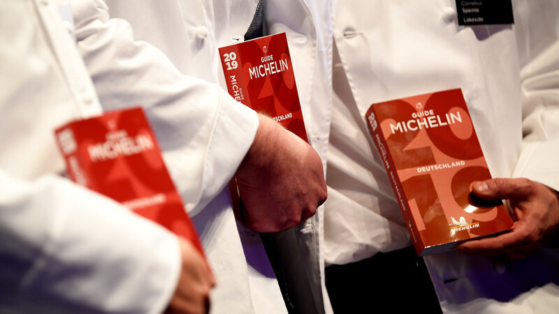 Sterneköche halten bei der Michelin Sterneverleihung 2019 den neuen Guide in der Hand.
