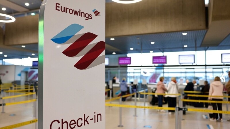 Reisende am Flughafen Köln/Bonn stehen in der Abflughalle an den Check-In Schaltern der Airline Eurowings.