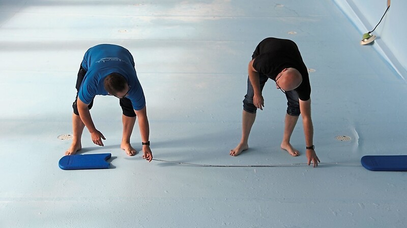 Jochen Seidl und Peter Wagner spielen mit, auf den Boden gelegten Schwimmbrettern das Szenario durch.